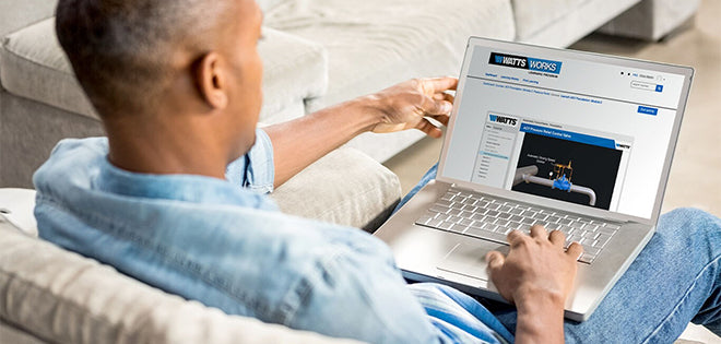 Person using a laptop on a couch, viewing a website with a visible brand logo.